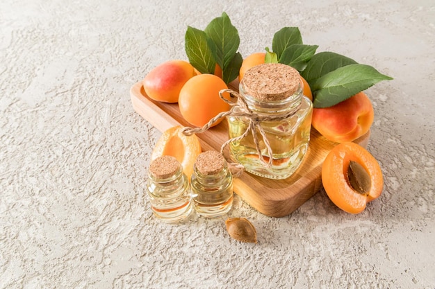 Garrafas de óleo de semente de damasco em uma bandeja de madeira com frutas maduras e um fundo de cimento cinza uma cópia do espaço orgânico de cuidados com a pele