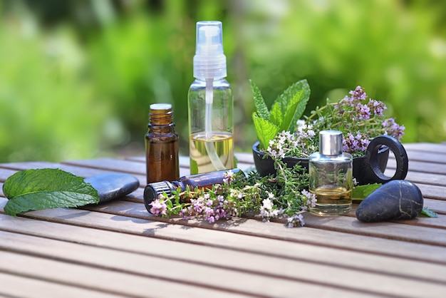 Garrafas de óleo essencial e flores de lavanda em uma mesa no jardim