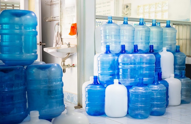 Garrafas de plástico azuis ou galões azuis de água potável são empilhados na fábrica de água potável