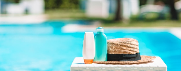 Garrafas de suncream, óculos de proteção, estrelas do mar na beira da piscina