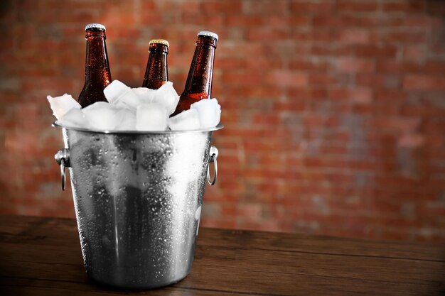 Foto garrafas de vidro castanhas de cerveja em icepail no fundo da parede de tijolos