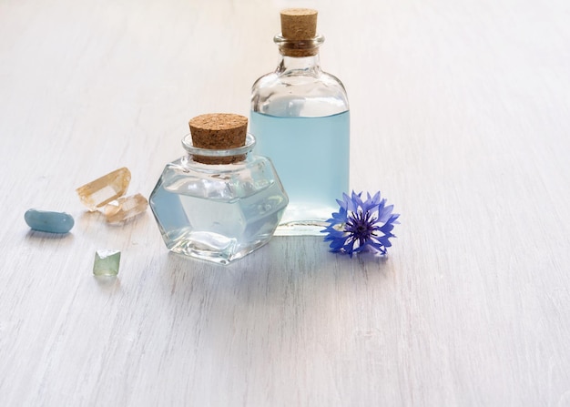 Garrafas de vidro com água de flor de centáurea azul ou minerais de óleo essencial em fundo branco