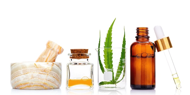 Garrafas de vidro de óleo de cannabis e folhas de cânhamo isoladas em branco. Conceito de uso de cânhamo na medicina.