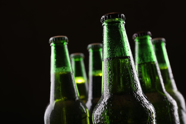 Garrafas de vidro verdes de cerveja em fundo escuro em close-up