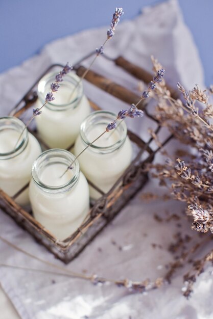 Garrafas de vidro vintage com flores de leite e lavanda em um fundo azul