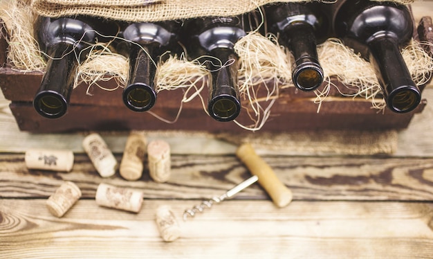 Garrafas de vinho vazias em uma caixa de madeira em uma tabela rústica.