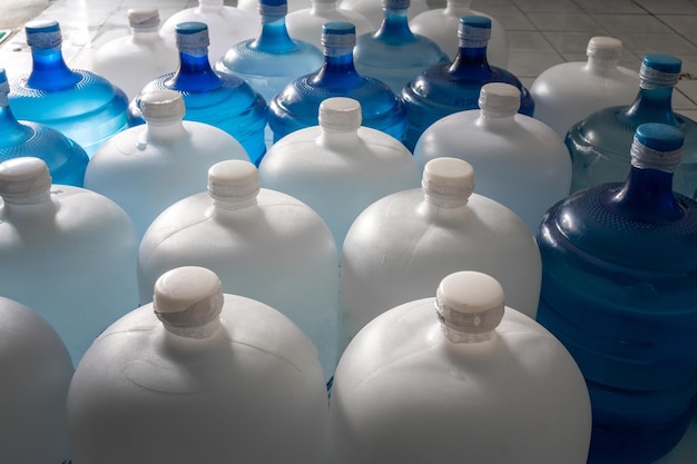 Garrafas grandes de plástico ou galões brancos e azuis de água potável purificada dentro da linha de produção