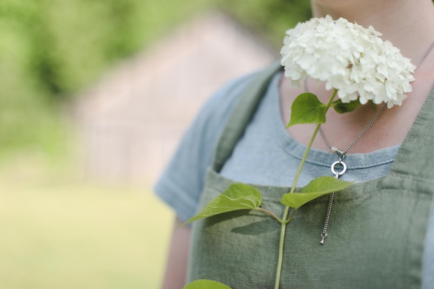 Garten- und Berufskonzept junge Frau in Schürze, die im Sommer Blumen im Garten hält