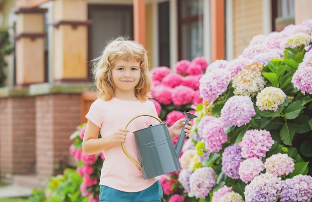 Gartenarbeiten. Gartenarbeit im Frühling. Kind mit Gießkanne im Garten. Blumen pflanzen und pflegen.
