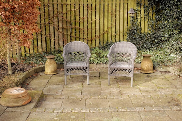 Gartenmöbel und Sitzgelegenheiten in einem abgelegenen und ruhigen Innenhof oder Hinterhof. Handgefertigte und rustikale Korbstühle auf der Terrasse zum Entspannen, Genießen und Meditieren in Zen und ruhiger Natur