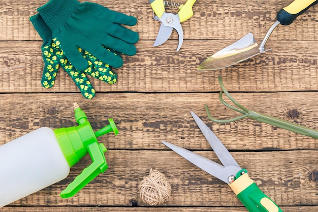 Gartenschere Rechen Drucksprüher Gartenhandschuhe Schaufel und Schutzbrille auf Brettern