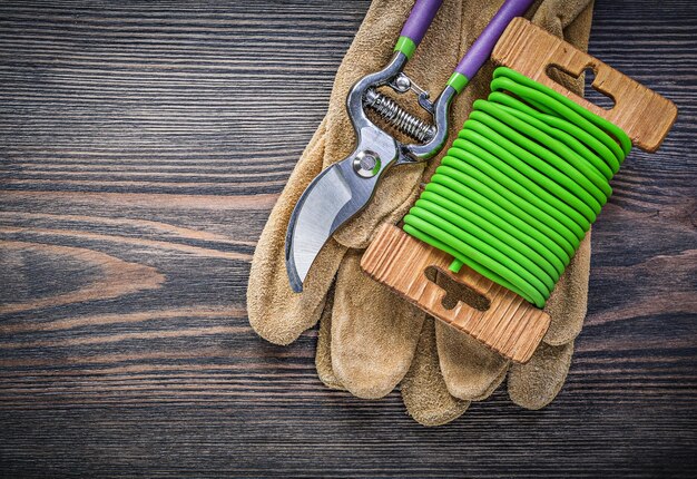 Gartenschere Sicherheitshandschuhe Gartenbindedraht auf Holzbrett Gartenkonzept