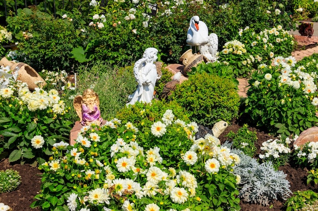 Gartenstatuen von Engeln und Tieren auf Blumenbeet