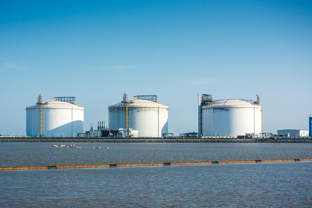 Foto gás natural liquefeito lng estação receptora terminal braço de descarregamento tanque de armazenamento céu azul e nuvens brancas imagem da atmosfera