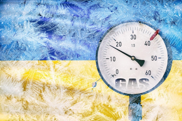 Gasdruckmesser auf dem Hintergrund der gefrorenen ukrainischen Flagge im Schnee