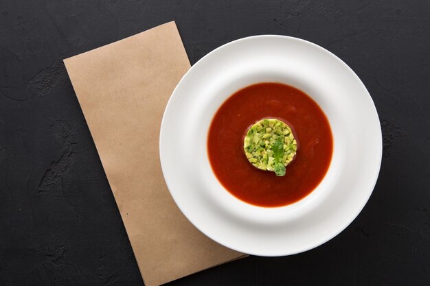 Gaspacho de sopa saborosa deliciosa de tomate frio com abacate. Porção de caldo de vegetais vermelho espanhol tradicional, serviço de restaurante, cópia espaço, vista de cima