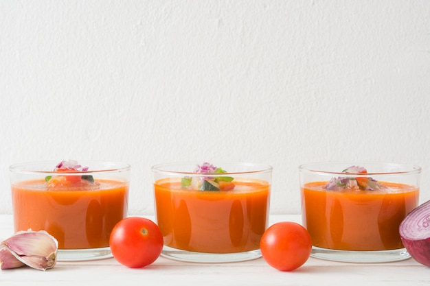 Gaspacho e ingredientes na mesa de madeira branca