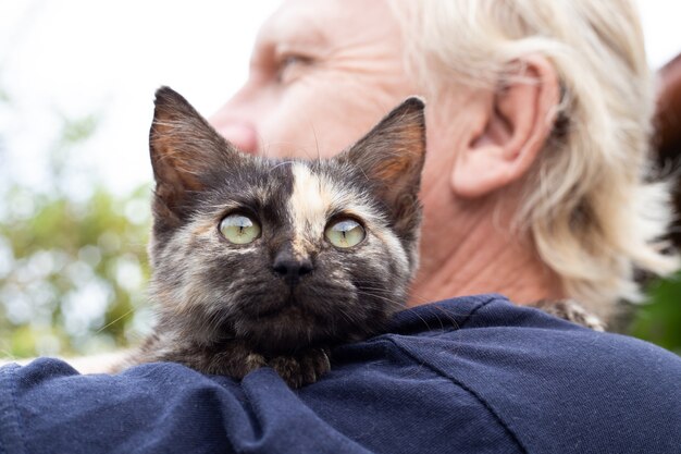 Foto un gatito con una tira en la nariz en el hombro de un hombre adulto. amor por las mascotas.