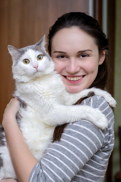 Gato blanco gris en manos de una joven