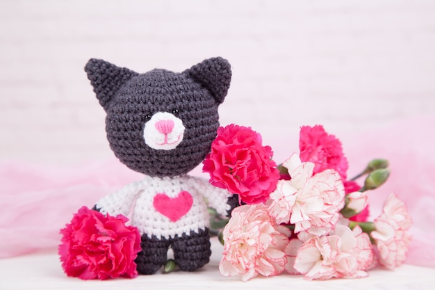 Gato de malha com um coração. Decoração de São Valentim. Brinquedo de malha, amigurumi. Cartão de dia dos namorados.