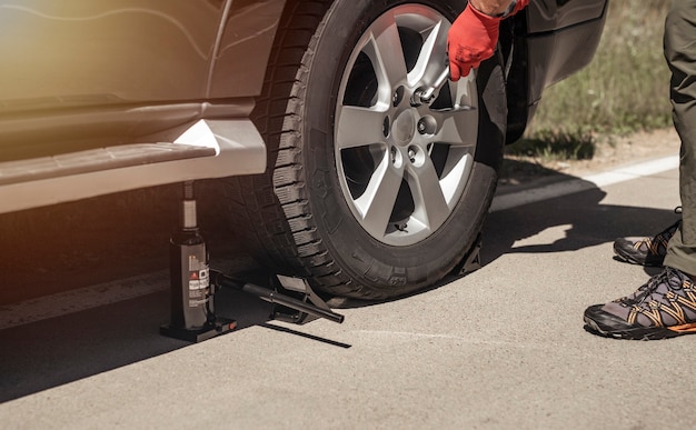 El gato hidráulico para coche se coloca debajo de auto con las manos en  guantes, primer plano Fotografía de stock - Alamy