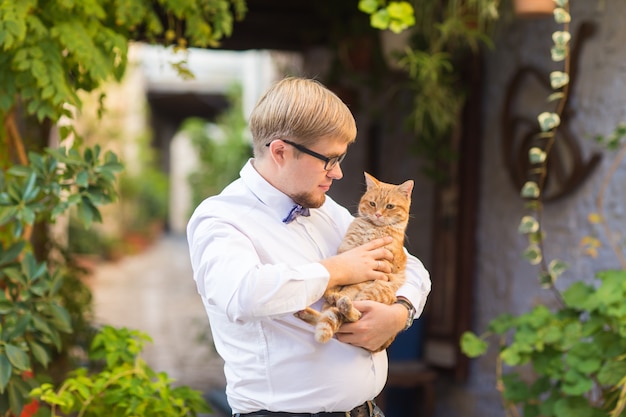 Gato rojo en manos del hombre elegante