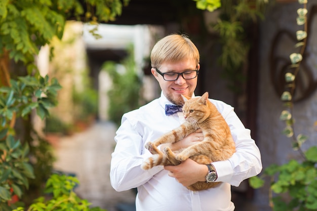 Gato vermelho nas mãos do homem elegante