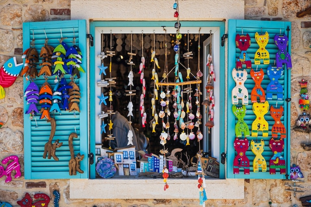 Gatos de madeira multicoloridos, casas e pequenos souvenirs de peixes estão em uma fila à venda em uma loja