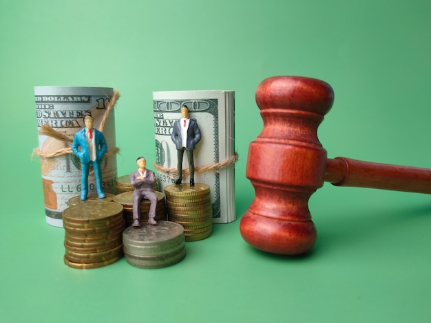 Gavelbanknotespersonas y monedas en miniatura sobre un fondo verde