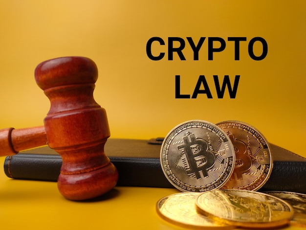 Gavelnotebook und Bitcoins mit Text CRYPTO LAW auf gelbem Hintergrund