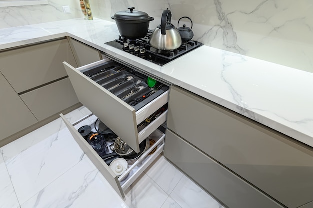 Gaveta aberta com talheres em cozinha de woden branca moderna em estilo clássico