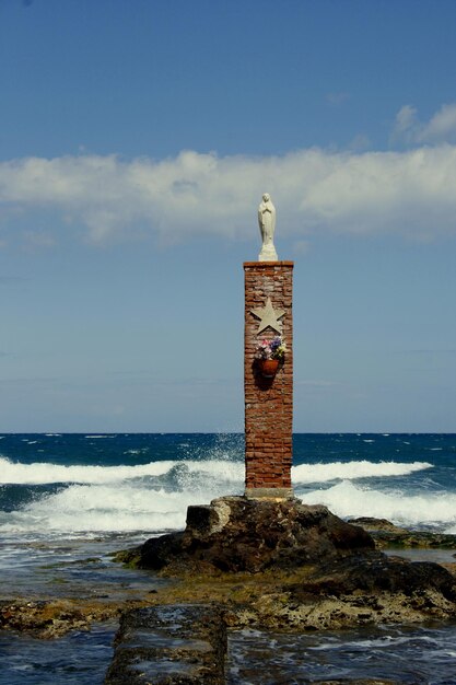 Foto la gaviota posada en el faro por el mar contra el cielo