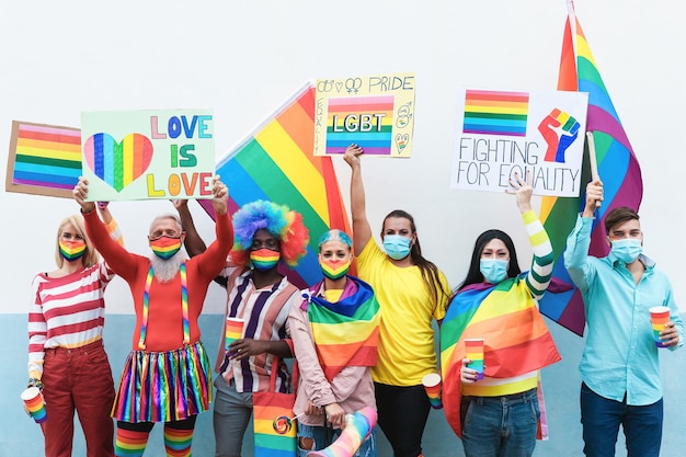 Gays multirraciales con máscara de arco iris en el desfile del orgullo lgbt al aire libre