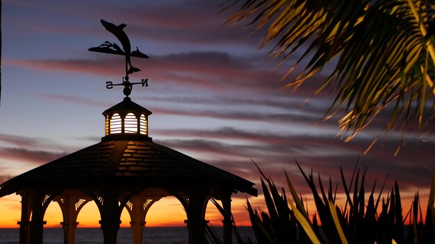 Gazebo de cloudscape al atardecer en la playa crepúsculo atardecer dramático cielo alcoba y veleta