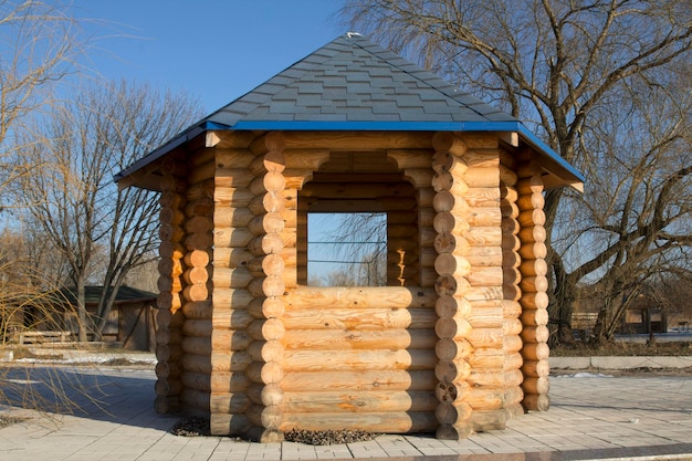 Gazebo hecho de troncos de madera contra el cielo y los árboles