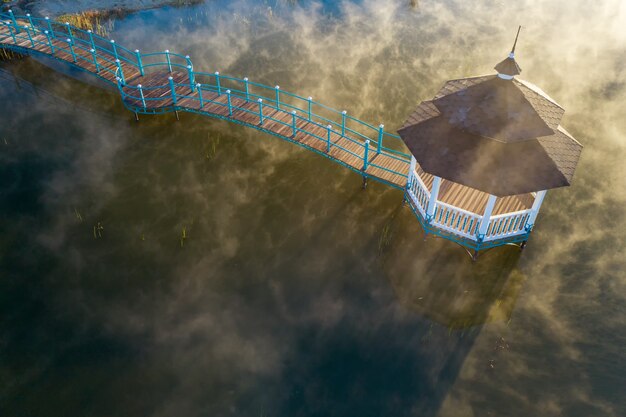 Gazebo en el lago al amanecer, vista superior humeante de agua