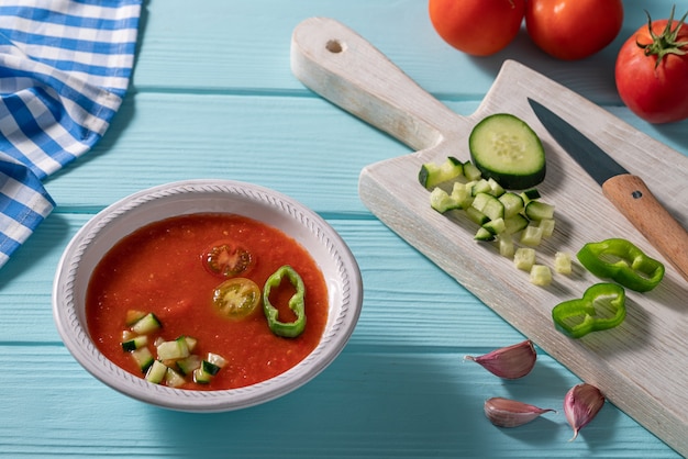 Foto gazpacho andaluz ist eine andalusische tomatensuppe aus spanien mit gurke, knoblauch, pfeffer auf hellblauem tisch