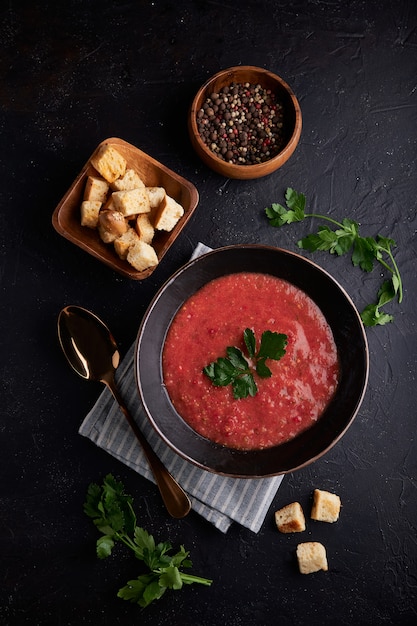 Gazpacho casero de tomate español con especias en un tazón negro