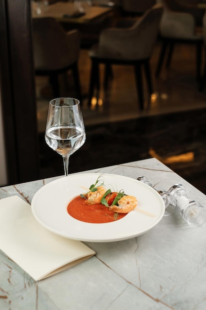 Gazpacho con gambas Sirviendo comida en un restaurante con vaso de agua y menú