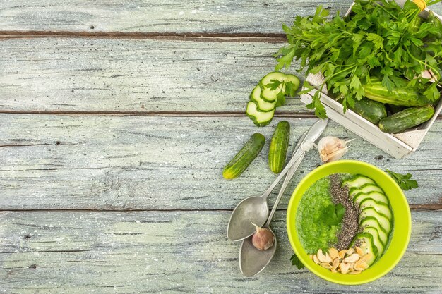 Gazpacho de Pepino. Sopa de verano fría fresca verde. Verduras frescas, verduras, especias y cubiertos. Fondo de tablas de madera vieja, vista superior