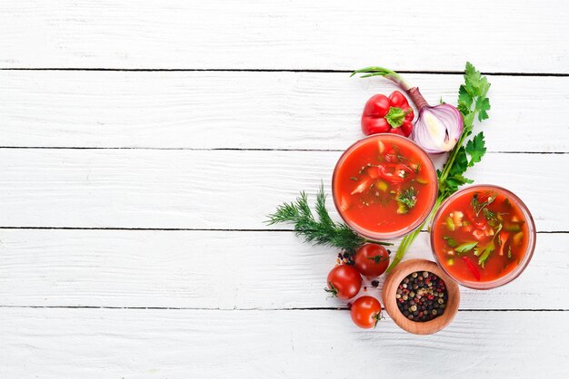 Gazpacho-Suppe im Glas Tomatensuppe mit Zwiebeln, Paprika und Petersilie Draufsicht auf weißem Holzhintergrund Freier Platz für Text