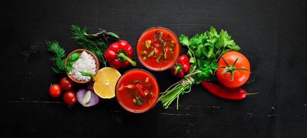 Gazpacho-Suppe im Glas Tomatensuppe mit Zwiebeln, Paprika und Petersilie italienische Küche Draufsicht auf schwarzem Hintergrund Freier Platz für Text