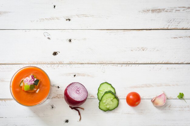 Gazpacho-Suppe in Glas und Zutaten auf weißem Holz