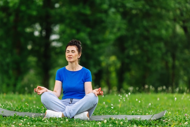 Gealterte Frau, die Yogaübung im Park tut. Übendes outdor Yoga der älteren Frau