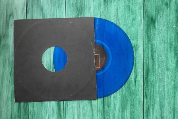 Gealterter schwarzer Papiereinband und blaue Vinyl-LP-Schallplatte isoliert auf grünem Hintergrund