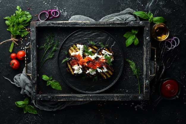Gebackene Auberginen mit Kaviar und Feta-Käse auf einem schwarzen Teller Flach legen Draufsicht Freier Kopierplatz