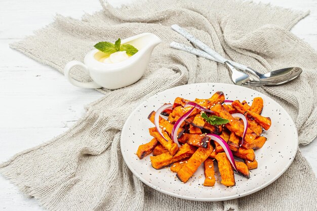 Gebackene Bio-Batata-Pommes mit Gewürzen und Soße. Süßes Gemüse serviert in Portionen und Besteck