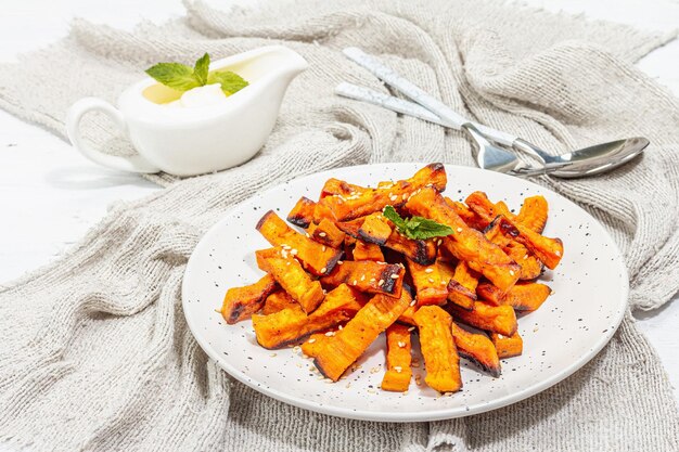 Gebackene Bio-Batata-Pommes mit Gewürzen und Soße. Süßes Gemüse serviert in Portionen und Besteck