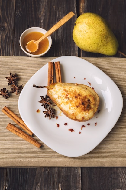 Gebackene Birne mit Ricotta-Käse, Honig und Zimt auf rustikalem Holzhintergrund. Gesundes und Diätessen. Ansicht von oben.