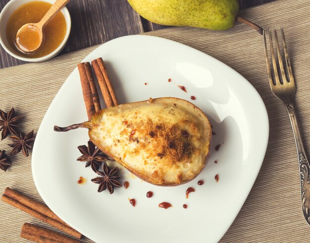 Gebackene Birne mit Ricotta-Käse-Honig und Zimt auf rustikalem Holzhintergrund